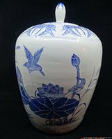 Porcelain jar showing blue painted birds and lotus on a cylindrical body with rounded lid knob
