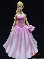 Full view of Barbie figurine in strapless pink dress holding pink wrapped gift.