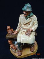 Front view of the Royal Doulton 'Lunchtime' figurine showing the man seated on a bench feeding squirrels.
