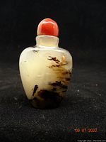 Front view of translucent moss agate snuff bottle showing organic brown and black dendritic inclusions inside the stone with red agate stopper on top.