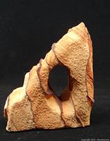 Front view of natural sandstone with window opening showing layered patterns and textures.