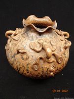 Front view of round Chinese stoneware vase showing scalloped rim and applied salamander-like clay motifs on mottled surface