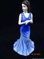 Front view of Royal Doulton porcelain figurine showing young woman in blue dress holding folded letter.