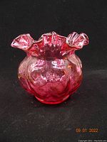 Front angle view showing the deep ruffled edge and quilted texture of the cranberry glass bowl.