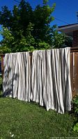 Curtain panels displayed outdoors hanging over a wooden fence, showing entire panel length and fabric drape in natural light.