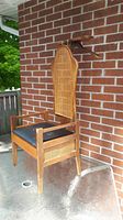 Solid wood valet chair with rattan backing, black faux leather seat with small tear, minor wood scuffs