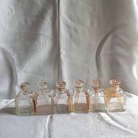 Front view of six square glass apothecary bottles in a row, showing consistent shape and size.