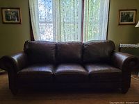 Full view of the brown leather sofa showing three seat cushions and rolled arms.