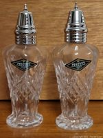 Pair of clear lead crystal salt and pepper shakers with silver tops, labeled Shannon Crystal Designs of Ireland.