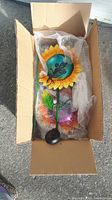 Set of two coloured metal fairy solar garden stake lights with sunflower design in open cardboard box wrapped in bubble wrap.