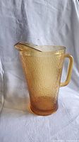 Side angle view of amber glass pitcher showing ribbed pattern and handle detail