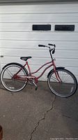 Full view of cherry pink adult cruiser bike showing frame, wheels, seat, and handlebar.