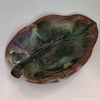 Top view of large leaf-shaped pottery dish with brown and green glossy glaze.