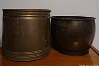 Overview of two large vintage brass planters side by side showing shape and relative size.