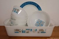 Full lot showing rectangular milk glass Pyrex baking dish, four small bowls with blue and gray prints, and a round plate with blue leaf border and dandelion design