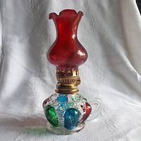 Front view of vintage mini oil lamp with colorful colored glass accents and red chimney