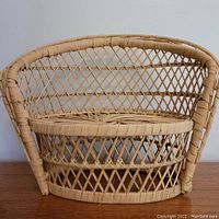 Front view of mini wicker love seat plant stand showing woven diamond lattice pattern and rounded armrests.