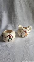 Photo of front and side view of cream and sugar set showing western cowboy and cowgirl designs with cactus.