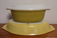 Side view of stacked yellow-green Pyrex casserole with a lid and one yellow dish underneath showing color and shape