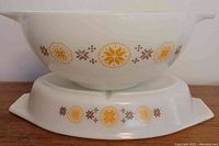 Side view of the Cinderella mixing bowl placed on top of the divided dish showing the yellow and brown floral/star pattern.