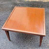 Full view of the square mid century coffee table showing the laminate top and wood frame.