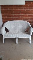Front view of white wicker loveseat showing overall shape and design.