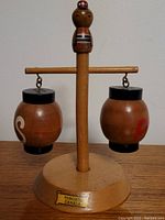 Full view of the vintage wooden salt and pepper shakers hanging from the stand, showing round base, vertical post topped with carved figure, and label marked "Toronto Canada" on the base.