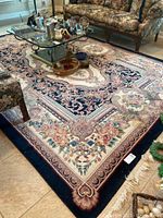 Full view of the area rug in living room with floral furniture and glass coffee table.