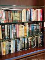Three full shelves of assorted hardcover and paperback books