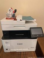 Front view of Canon MF634Cdw printer showing touchscreen and accessories on top