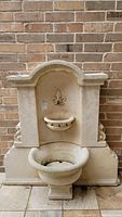 Front view of concrete fountain against brick wall
