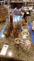 Photo displaying the entire set arranged on a granite countertop including six glass mugs with copper bases and handles, copper spoons, copper salt shaker, cinnamon grinder, glass bowl with silver holder, candle holder, and decorative glass bottles.