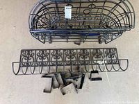 Photo showing the large curved metal garden basket, one smaller decorative basket, and multiple metal brackets laid out on floor.