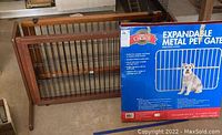 Wood and metal expandable pet gate with vertical bars, medium wood finish, shown next to boxed Great Choice expandable metal pet gate