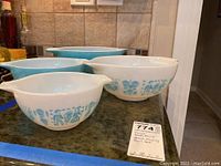 Four Pyrex Butterprint Amish mixing bowls arranged on counter showing sides and pattern details.