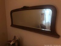 Side angle view showing the thickness of the wood frame and carved bow detail on top