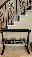 Photo of the dumbbell rack against a wall with multiple hex dumbbells on the lower bars.