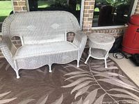 Photo of white wicker couch, side table, and outdoor rug showing condition and pattern detail.