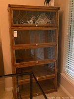 Front view of the tall wooden cabinet showing all five glass doors, including the top patterned glass door, knobs, and wood finish.