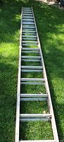 Full length view of ladder laid out on grass, showing overall condition and dirt from outdoor storage.