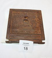 Cast iron stove door showing front with embossed manufacturer and model details, heavily rusted.