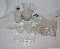 Photo of all glass serving pieces including decanter, pitcher, trays, dishes, and bowl with decorative pineapple