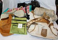 Photo showing a variety of handbags including brown perforated leather, green fabric crossbody, black shiny handbags, beige and cream canvas bags, and floral patterned fabric bag.