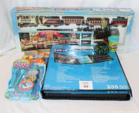 Overall lot showing the toy train set in a box, two Aqua Sand packs, art set, marbles, and Play-Doh container