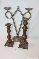 Front view of the large silver-toned metal double candle holder with two brown wooden candle holders positioned in front.