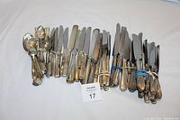 Photo showing the entire collection of silverplated utensils laid out grouped in bundles by type including forks, knives, and spoons on a white cloth background.
