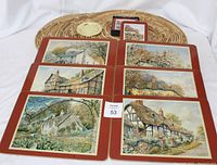 Six rectangular placemats with images of English houses, each with a matching coaster, plus three large oval wicker placemats and two small brass-colored coasters arranged on a white background.