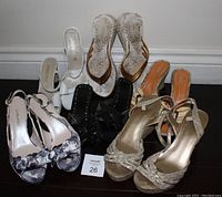 Six pairs of women's summer shoes including floral prints, white, black, gold, and striped wedge sandals.