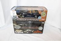 Two die cast model cars in original boxes stacked; top is black PT Cruiser Convertible Styling Study, bottom is black 2001 Harley Davidson F-150 Super Crew Pickup model