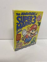 Front view of the yellow slipcase for The Adventures of Super Mario Bros. 3 DVD complete series, showing Mario in raccoon form on the cover
